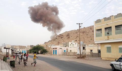 TOPSHOT - Yemenis run for cover as smoke rises following a car bomb attack at an army checkpoint at the entrance to the town of Hajr, located some 15 kilometres (nine miles) to the west of Mukalla, the capital of Yemen's southeastern Hadramawt province on July 18, 2016. Suicide bombers attacked two army checkpoints in a former stronghold of Al-Qaeda in southeastern Yemen, killing 11 people, health and security officials said.n / AFP / ABDULJABBAR BAJUBAIR