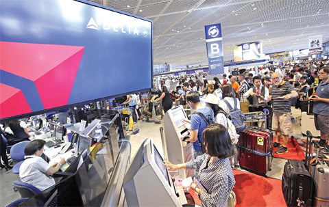 TOKYO: Passengers check in at the Delta Air Lines counter at Narita international airport in Narita, east of Tokyo, yesterday. More than 1,000 people spent the night at the Narita airport because of a computer shutdown that halted Delta Air Lines flights worldwide. — AP