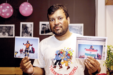 Indian climber, Satyarup Sidhantha holds on his right hand a photograph that shows him on Mount Everest, along with what he says is an altered version of the same used by an Indian couple to make it appear they were on the summit, as he displays them for the Associated Press in Kolkata, India. — AP