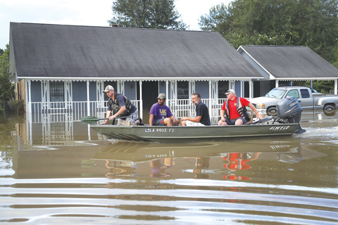LOUISIANA: Richard Schafer navigates a boat past a flooded home in Baton Rouge, Louisiana. — AFP