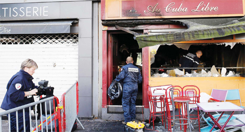 ROUEN, France: Police officers and fire investigators walk into the damaged Au Cuba Libre bar yesterday after a fire broke out overnight in the bar during a birthday party.— AFP