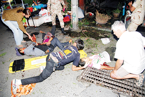 In this Thursday, Aug. 11, 2016, photo, the injured are helped after a bomb blast in the southern resort city of Hua Hin, 240 kilometers (150 miles) south of Bangkok, Thailand. Police are investigating a series of bomb blasts in Hua Hin and other cities in Thailand. (Daily News via AP)