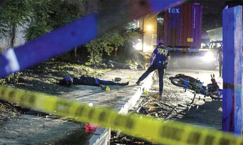 MANILA: Philippine Scene of the Crime Operatives (SOCO) work at the scene where two suspects were shot dead following an encounter and shootout with police at a checkpoint along a highway in Manila yesterday. — AFP