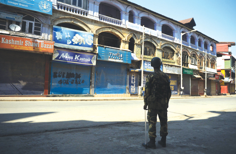 SRINAGAR: An Indian paramilitary trooper stands guard during a curfew in the Lal Chowk area yesterday. —AFP