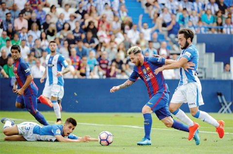 LEGANES: Barcelona’s Argentinian forward Lionel Messi (C) vies with Leganes’ midfielder Unai Lopez during the Spanish league football match CD Leganes CF vs FC Barcelona at the Butarque municipal stadium in Leganes yesterday. — AFP