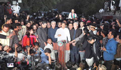 ISLAMABAD: Politician Imran Khan, center, is surrounded by his supporters as he speaks to journalists outside his residence. — AP