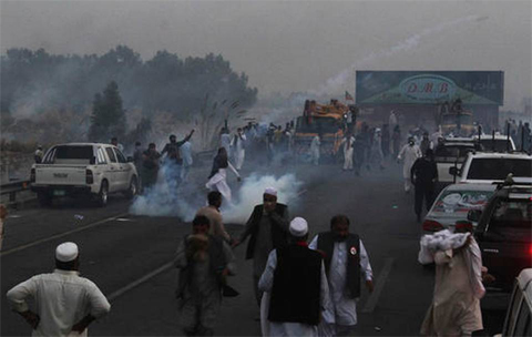 A supporter of Pakistan's Tehreek-e-Insaf party, headed by cricketer turned politician Imran Khan throws tear gas shell back to police during a clash in Hazro, Pakistan, Monday, Oct. 31, 2016. Pakistani police launched a nation-wide crackdown overnight, arresting at least 1,500 supporters of Khan ahead of an opposition rally planned later this week in Islamabad, officials said Monday. AP Photo