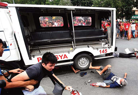MANILA: Protesters lie on the ground after being hit by a police van during a rally in front of the US embassy. —AFP