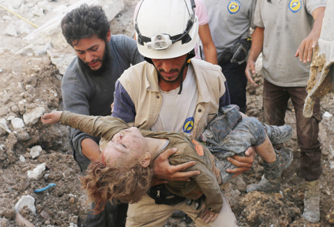 ALEPPO: A Syrian civil defense volunteer holds the body of a child after he was pulled from the rubble following a government air strike on the rebel-held neighborhood of Karm Homad in this northern city yesterday. – AFP 