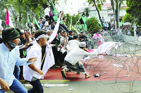 Muslim protesters pull razor wire blocking a road that leads to the presidential palace during a rally against Jakarta Governor Basuki Tjahaja Purnama in Jakarta, Indonesia, Friday, Nov. 4, 2016. Tens of thousands of hard-line Muslims marched Friday on the center of the Indonesian capital to demand the arrest of the minority-Christian governor for alleged blasphemy. (AP Photo/Tatan Syuflana)