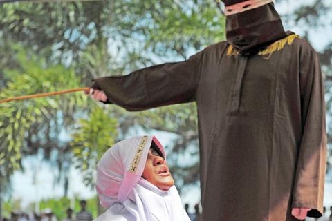 BANDA ACEH: A religious officer canes an Acehnese woman for spending time in close proximity with a man who is not her husband. — AFP