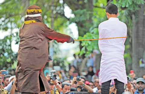 BANDA ACEH: A religious officer canes an Acehnese man 100 times for having sex outside marriage, which is against sharia law, in Banda Aceh yesterday. — AFP