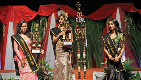 In this file photo, Qienabh Tappii, center, holds her trophy as she stands on the stage with first runner up Sefty Castanyo, left, and third place winner Amanda Sandova, right, after winning the Miss Transgender Indonesia pageant in Jakarta, Indonesia.