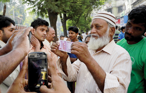 MUMBAI: An Indian displays a new Rupees 2,000 currency note outside a bank in Mumbai yesterday. — AP