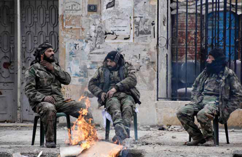 ALEPPO: Syrian soldiers sit by a fire in the former rebel-held Ansari district in the northern Syrian city of Aleppo yesterday. —AFP