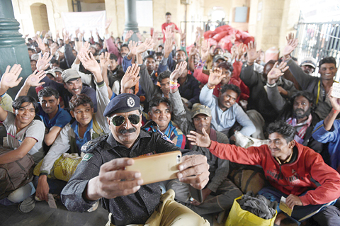 KARACHI: A Pakistani policeman takes a selfie with Indian fishermen at the railway station in Karachi yesterday, after their release from prison.