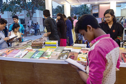 DHAKA: Bangladeshi shoppers read books at a stall during the country’s largest bookfair in Dhaka yesterday. Bangladesh’s largest book fair began in Dhaka yesterday, with police warning organizers against selling books that hurt ‘religious sentiment’ in the Muslim-majority country. —AFP