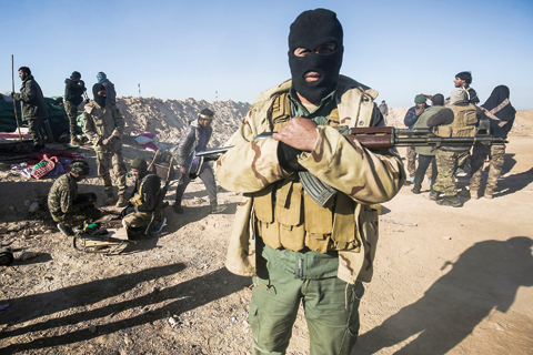 A masked fighter of the Hashed Al-Shaabi (Popular Mobilization) paramilitaries poses for a picture carrying a Kalashnikov assault rifle by defensive positions near the frontline village of Ayn Al-Hisan, on the outskirts of Tal Afar west of Mosul, where Iraqi forces are preparing for the offensive retake the western side of Mosul from Islamic State (IS) group fighters. —AFP