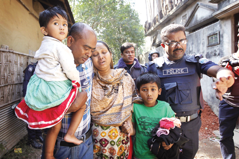 SITAKUNDA: A Bangladeshi policeman evacuates a family after cordoning off the area where suspected militants were holding up, in Sitakunda in Chittagong district of Bangladesh, yesterday.—AP