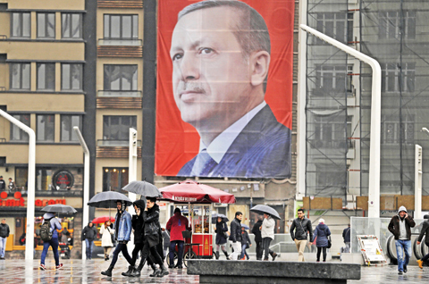ISTANBUL: People walk in central Istanbul’s Taksim Square, back dropped by a poster of Turkish President Recep Tayyip Erdogan. — AP