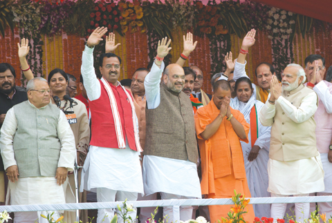 LUCKNOW: Indian Prime Minister Narendra Modi, second right and Yogi Adityanath, in saffron robes, greet with folded hands as Bharatiya Janata Party president Amit Shah, center and others wave to the audience after Adityanath was sworn in as Uttar Pradesh state chief minister in Lucknow, India, yesterday.-AP