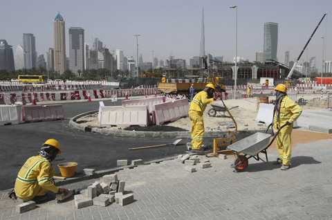 DUBAI: Laborers work at a road construction site on Monday. - AP 