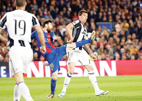 BARCELONA: Barcelona's Lionel Messi fights for the ball with Juventus' Mario Mandzukic, right, during the Champions League quarterfinal second leg soccer match between Barcelona and Juventus at Camp Nou stadium in Barcelona, yesterday. — AP