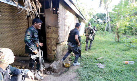 INABANGA: Police and soldiers take position as they engage with the Abu Sayyaf group in the village of Napo, Inabanga town, Bolo province, in the central Philippines yesterday. — AFP