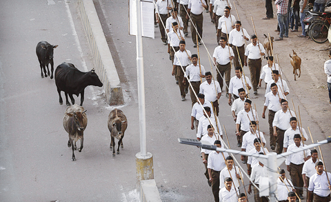 ALLAHABAD, India: In this March 26, 2017 photo, stray cows roam on a street as volunteers of the Hindu nationalist organization Rashtriya Swayamsevak Sangh march to mark Vikram Samvat’s new year. —AP