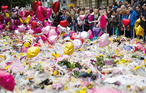 MANCHESTER: People look at flowers and balloons in St Ann’s Square yesterday, placed in tribute to the victims of the May 22 terror attack at the Manchester Arena. —AFP