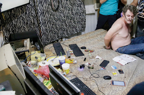MABALACAT: A suspected child webcam cybersex operator, David Timothy Deakin (from Peoria, Ill., with his hands tied behind his back) is seen during a raid by investigators. — AP