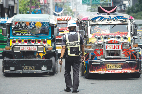 MANILA: Jeepneys are seen as an enforcer manages traffic on a busy street yesterday. — AFP