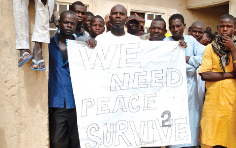 MAIDUGURI, Nigeria: Nigerian IDPs (Internal Displaced Persons) hold a placard reading “we need peace to survive” during the visit of Nigerian Vice President Yemi Osinbajo to the Bakassi IDPs camp on June 8, 2017. — AFP