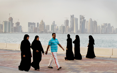 DOHA: With the new high-rise buildings of downtown Doha in the background, Qatari women and a man enjoy walking by the sea in Doha. — AP