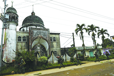 MARAWI: Philippine Marines walk past a mosque during a patrol along a deserted street at the frontline. – AFP