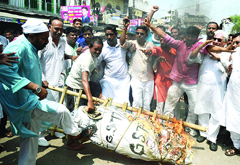 This photo taken on June 30, 2017 shows Indian traders shouting slogans as they burn an effigy of Finance Minister Arun Jaitley during a protest against the new Goods and Services Tax (GST) in Allahabad. India is bracing for its most significant reform in a generation as the world's fastest growing major economy is unified into a single market for the first time with the introduction of the Goods and Services Tax (GST) on July 1. - TO GO WITH AFP STORY INDIA-ECONOMY-TAXATION-GSTn / AFP / SANJAY KANOJIA / TO GO WITH AFP STORY INDIA-ECONOMY-TAXATION-GST