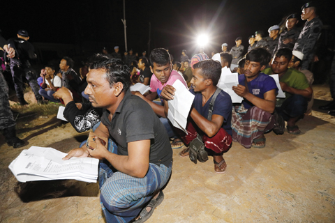 MALAYSIA: Foreign workers wait for their work documents to be checked by Malaysian immigration officer during an operation to crackdown on illegal immigration on the outskirts of Port Dickson. — AP