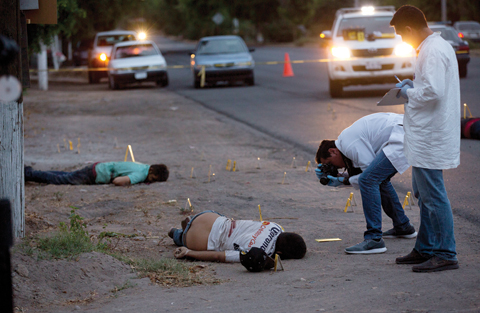 SINALOA STATE: Investigators take pictures at the crime scene next to bodies lying on a road in the town of Navolato, Sinaloa state, Mexico. 59 AK type and AR-15 bullet casings were found in the area. — AP
