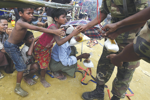 GUMDHUM: Bangladeshi soldiers distribute rice to young Rohingya refugees at the refugee camp of Balukhali. — AFP