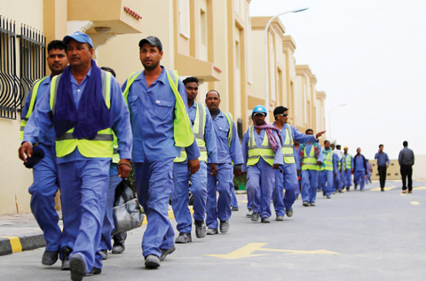 This file photo taken on May 4, 2015 shows foreign laborers working on the construction site of the al-Wakrah football stadium, one of the Qatar's 2022 World Cup stadiums, walking back to their accomodation at the Ezdan 40 compound after finishing work on May 4, 2015, in Doha's Al-Wakrah southern suburbs. World Cup 2022 host Qatar, under global scrutiny over its alleged ill-treatment of migrant labourers, is to introduce a minimum wage for workers, official state media said on October 25, 2017. / AFP 