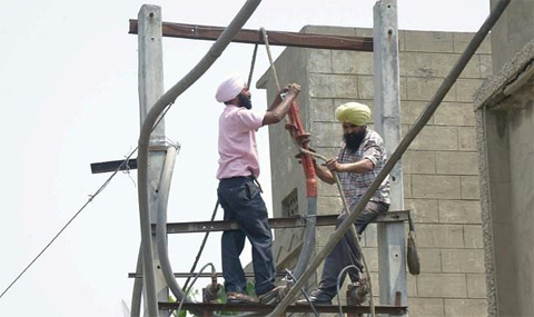 Workers repair an electricity pylon in Amritsar in April: India's transmission system is in poor shape AFP