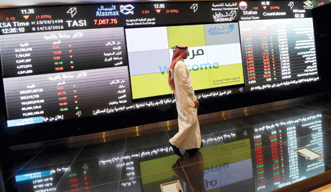 RIYADH: This file photo shows a Saudi investor walking past the stock exchange monitors at the Saudi Stock Exchange or Tadawul, in Riyadh. — AFP