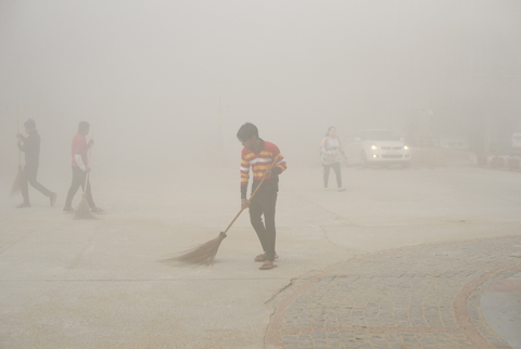 NEW DELHI: Indian workers use brooms to sweep away dust in the morning fog in Greater Noida, near New Delhi. A thick gray haze has enveloped India’s capital region as air pollution hit hazardous levels. —AP