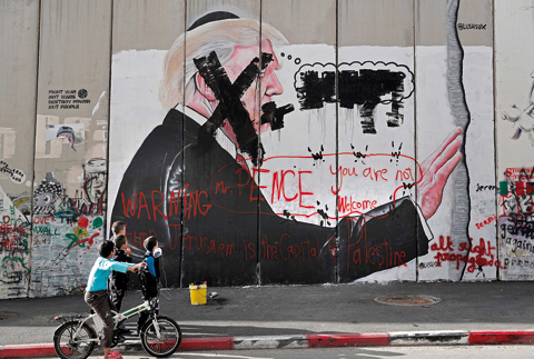 BETLEHEM: Palestinian children look at vandalized graffiti depicting US President Donald Trump and slogans against US Vice President Mike Pence painted on Israel’s controversial separation barrier in the West Bank city of Bethlehem during clashes with Palestinian protestors near an Israeli checkpoint yesterday. —AFP