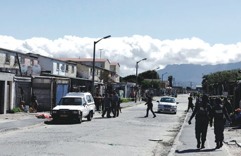 CAPE TOWN: Residents gather as South African police officers respond to a shooting of two alleged gang members in Manenberg, Cape Town. — AFP