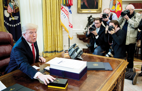 WASHINGTON DC: US President Donald Trump offers pens to the press after signing a tax reform bill in the Oval Office of the White House on Friday in Washington, DC. —AFP