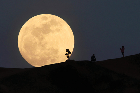 A person poses for a photo as the moon rises over Griffith Park in Los Angeles, California, on January 30, 2018. Many parts of the globe may catch a glimpse on January 31 of a giant crimson moon, thanks to a rare lunar trifecta that combines a blue moon, a super moon and a total eclipse. The spectacle, which NASA has coined as ‘super blue blood moon.’ — AFP