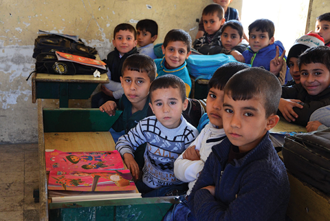 Iraqi children pose for a photo in a classroom in the battered city of Mosul