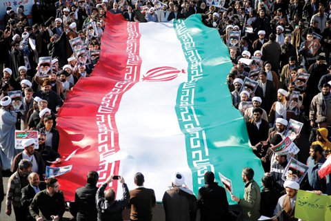   QOM, Iran: Pro-government demonstrators wave their national flag during a march yesterday. - AFP