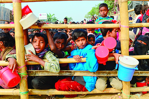 TOPSHOT - Rohingya Muslim refugees wait for food aid at Thankhali refugee camp in Bangladesh's Ukhia district on January 12, 2018.nAbout 655,000 Rohingya have escaped to Bangladesh since August 2017 after the Myanmar army began a campaign of rape and murder in Rakhine state. They joined the more than 200,000 refugees already living in Bangladesh who had fled previous violence in Rakhine. / AFP PHOTO / Munir UZ ZAMAN